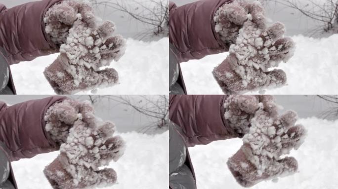 冬天，孩子戴着针织手套的手拿着第二只手套，上面覆盖着粘稠的雪块
