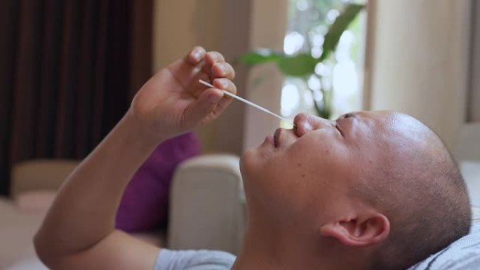 一名亚洲男子把头躺在沙发上，闭着眼睛，拿着一根白色棍子的视频