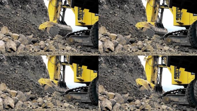 一辆黄色的大型卡特彼勒挖掘机正在将土壤和矿石收集到铲斗中。采石场，金属开采。从地面射击。4K