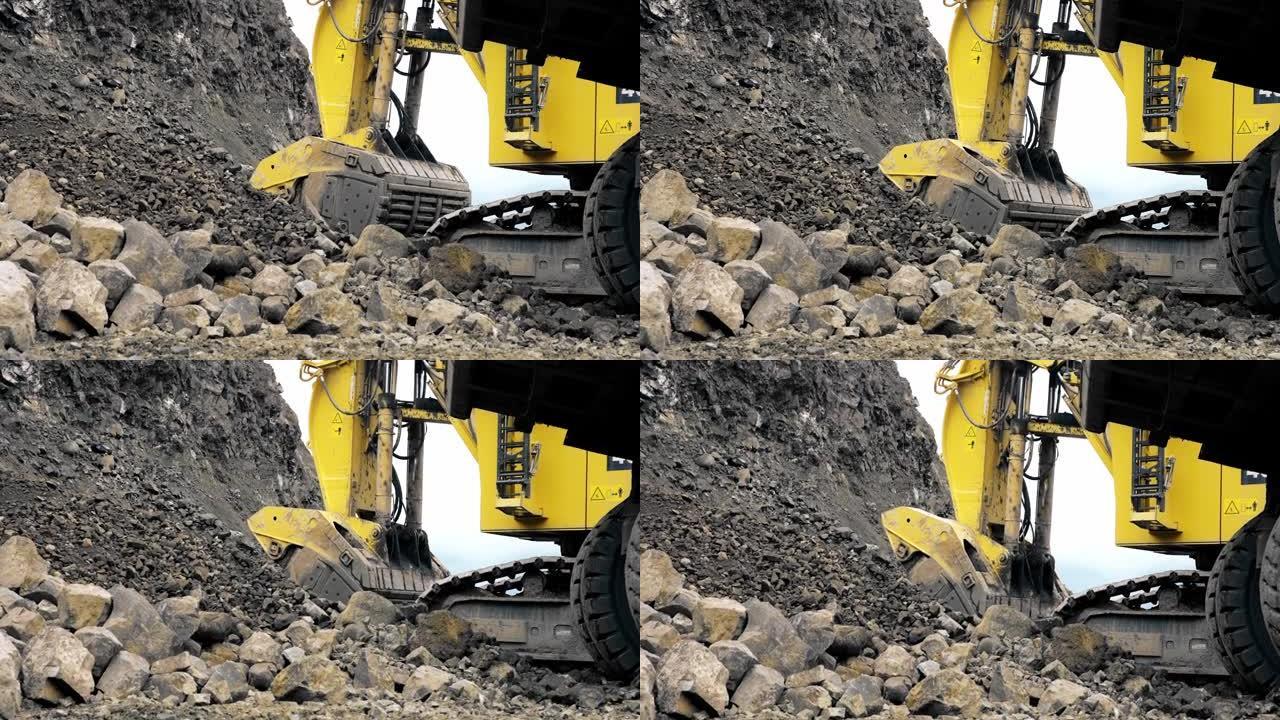 一辆黄色的大型卡特彼勒挖掘机正在将土壤和矿石收集到铲斗中。采石场，金属开采。从地面射击。4K