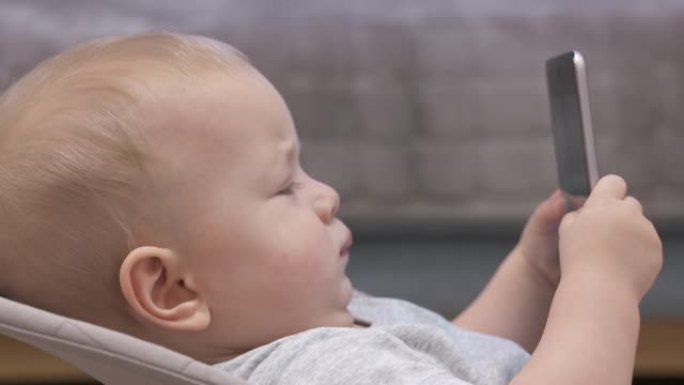 儿童使用移动设备，儿童手持平板电脑，9个月大的男婴在平板电脑屏幕上观看儿童动画电视连续剧。