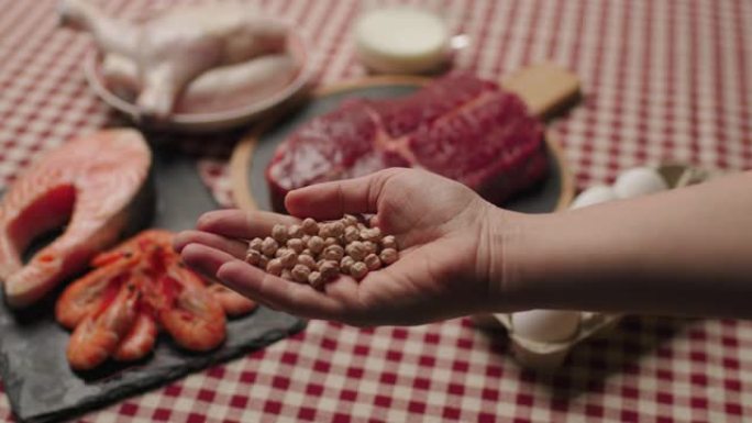 手里拿着鹰嘴豆，桌上有蛋白质食物。蛋白质含量高的产品。