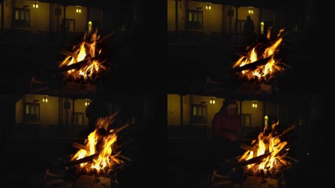男孩在村舍花园的篝火旁温暖双手。