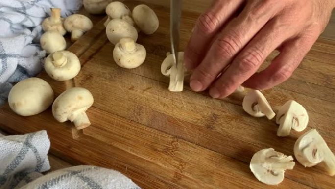 中年男子用刀在餐桌旁准备蘑菇