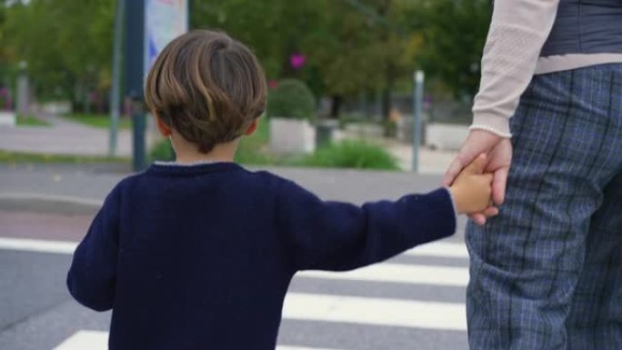 母亲带着孩子过街。小男孩与父母牵着手在人行横道上