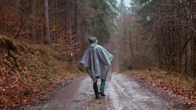 穿着雨衣的人走过森林，下雨，孤独，秋天和冬天，男人内心深处，反思。