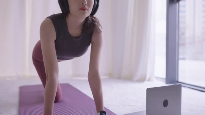 年轻的亚洲女性在室内练习瑜伽并穿着瑜伽服