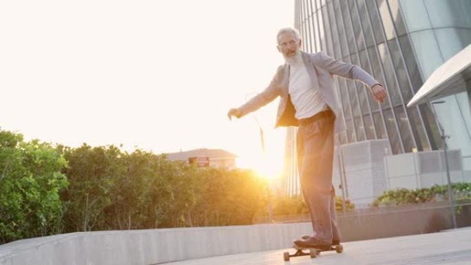 活跃的老年商业男子滑冰运动员穿着西装骑滑板在城市。