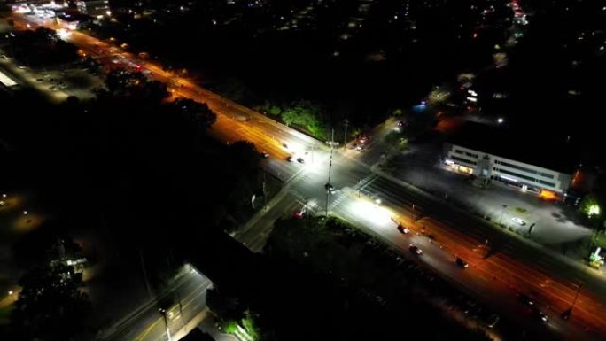 晚上十字路口的鸟瞰图。摄像机向下倾斜，卡车向右平移，向左平移，以保持十字路口居中。该地区很暗，但道路