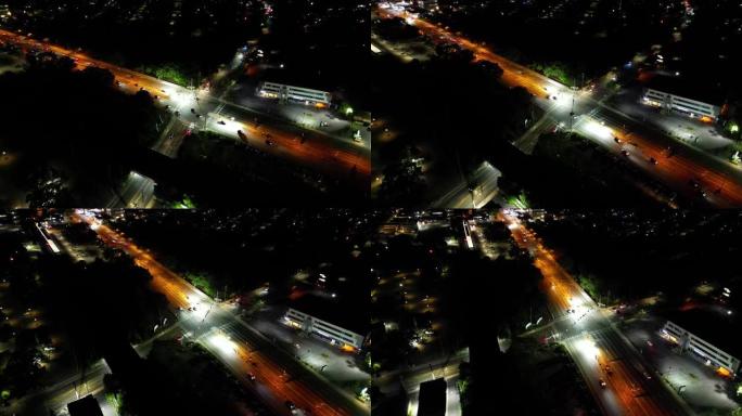 晚上十字路口的鸟瞰图。摄像机向下倾斜，卡车向右平移，向左平移，以保持十字路口居中。该地区很暗，但道路