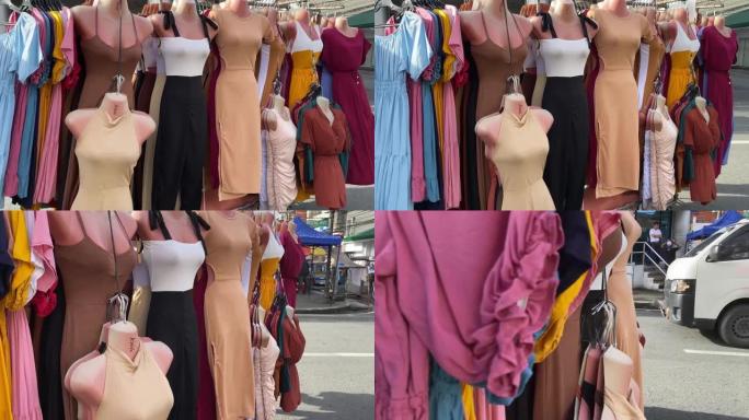 礼服和女装挂在路边，由城镇节日期间沿街的边缘小贩展示和出售。
