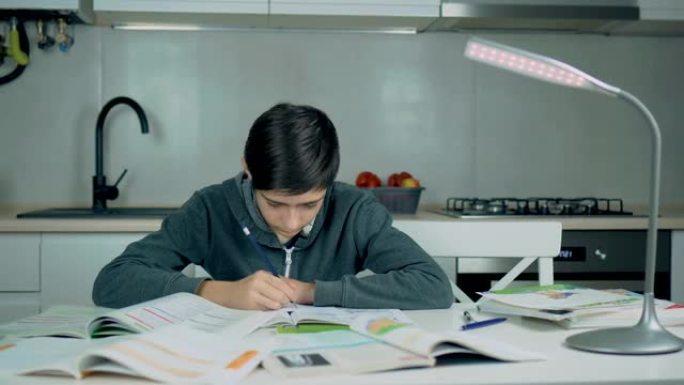聪明的学校男孩学习写作做数学作业坐在家里的桌子上