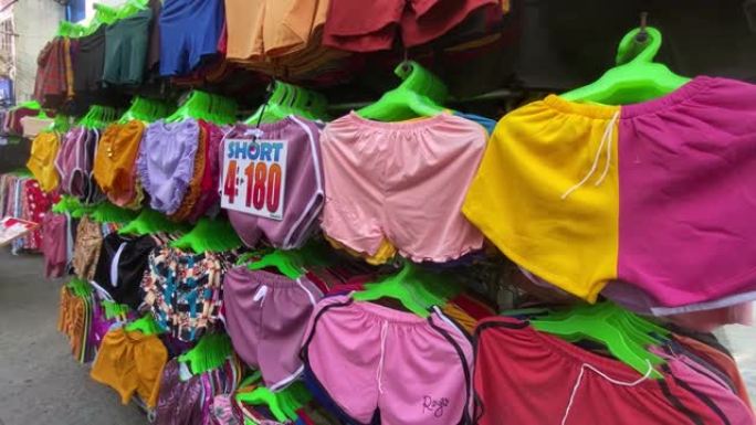 妇女的内衣和短裤挂在路边，由城镇节日期间沿街的边缘小贩展示和出售。