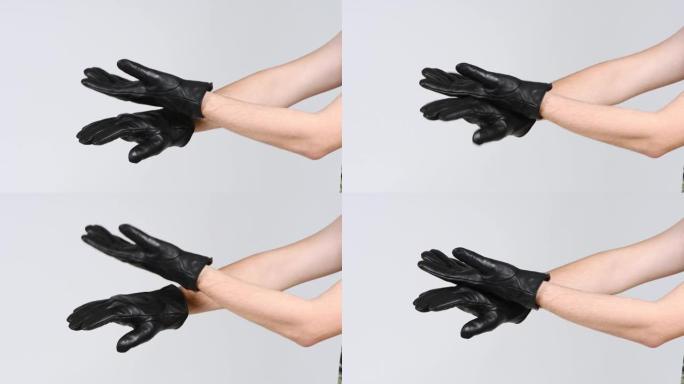 一个戴着黑色手套的男人用手背拍手。侧视图。