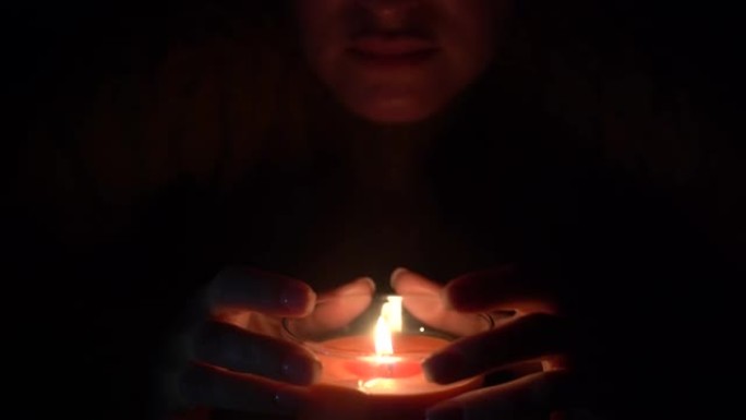 蜡烛在一个黑色美女手持的玻璃杯中点燃。孤立在节约地球能源的概念上。地球一小时