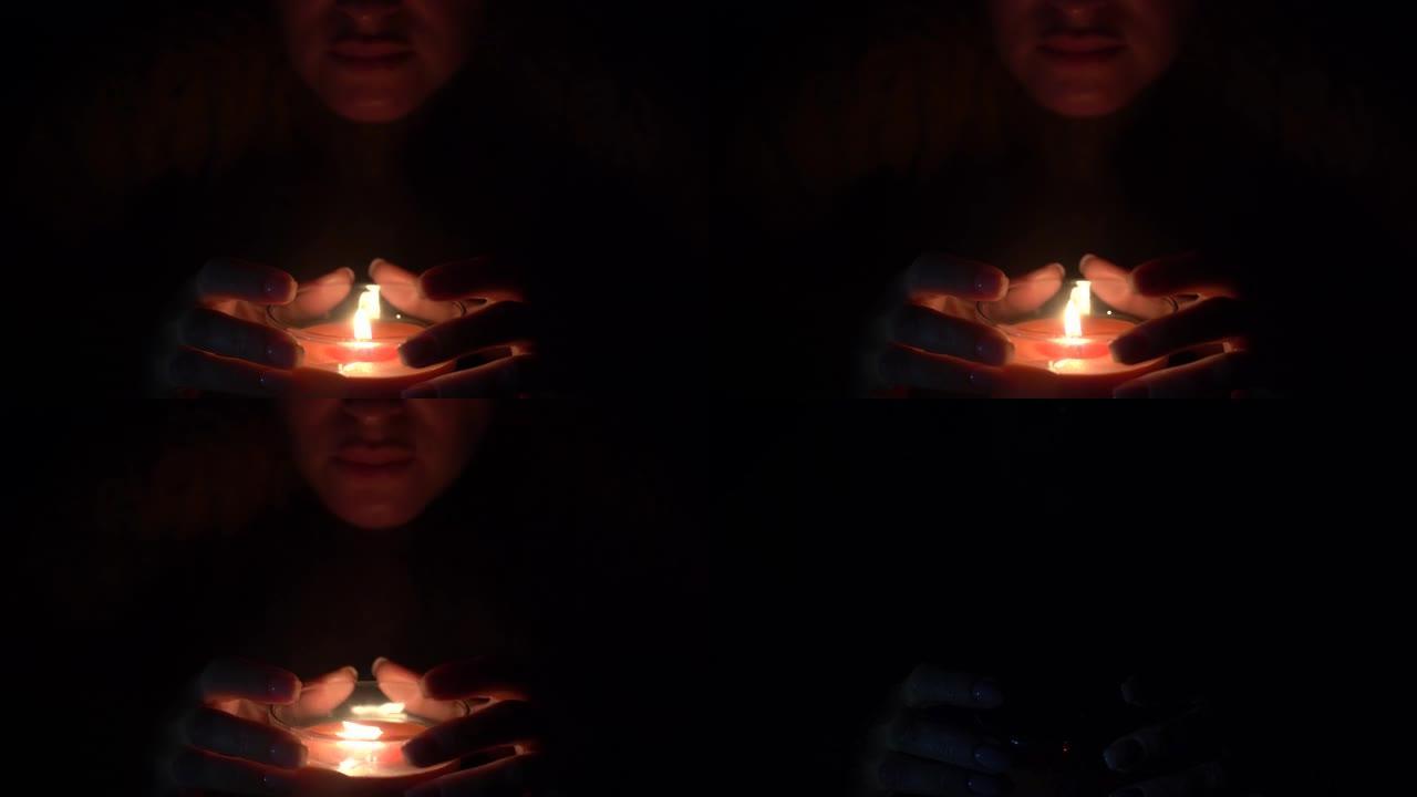蜡烛在一个黑色美女手持的玻璃杯中点燃。孤立在节约地球能源的概念上。地球一小时