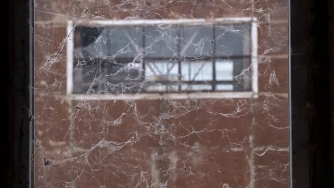一栋废弃建筑里有蜘蛛网的旧脏窗户。