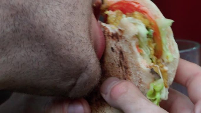 年轻人在特写镜头中吃性感多汁的牛肉汉堡