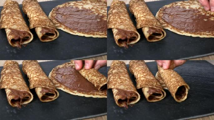 卷起薄饼，上面铺有榛子巧克力奶油，放在一块方形的黑色石板上，再加上两个现成的薄饼