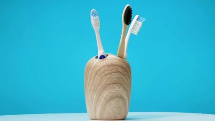 一组牙刷在蓝色背景的转盘上旋转。陶瓷外壳中的牙刷工作室拍摄