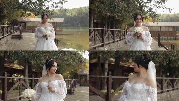 美丽时尚的新娘穿着白色婚纱和面纱，手捧婚礼花束在公园