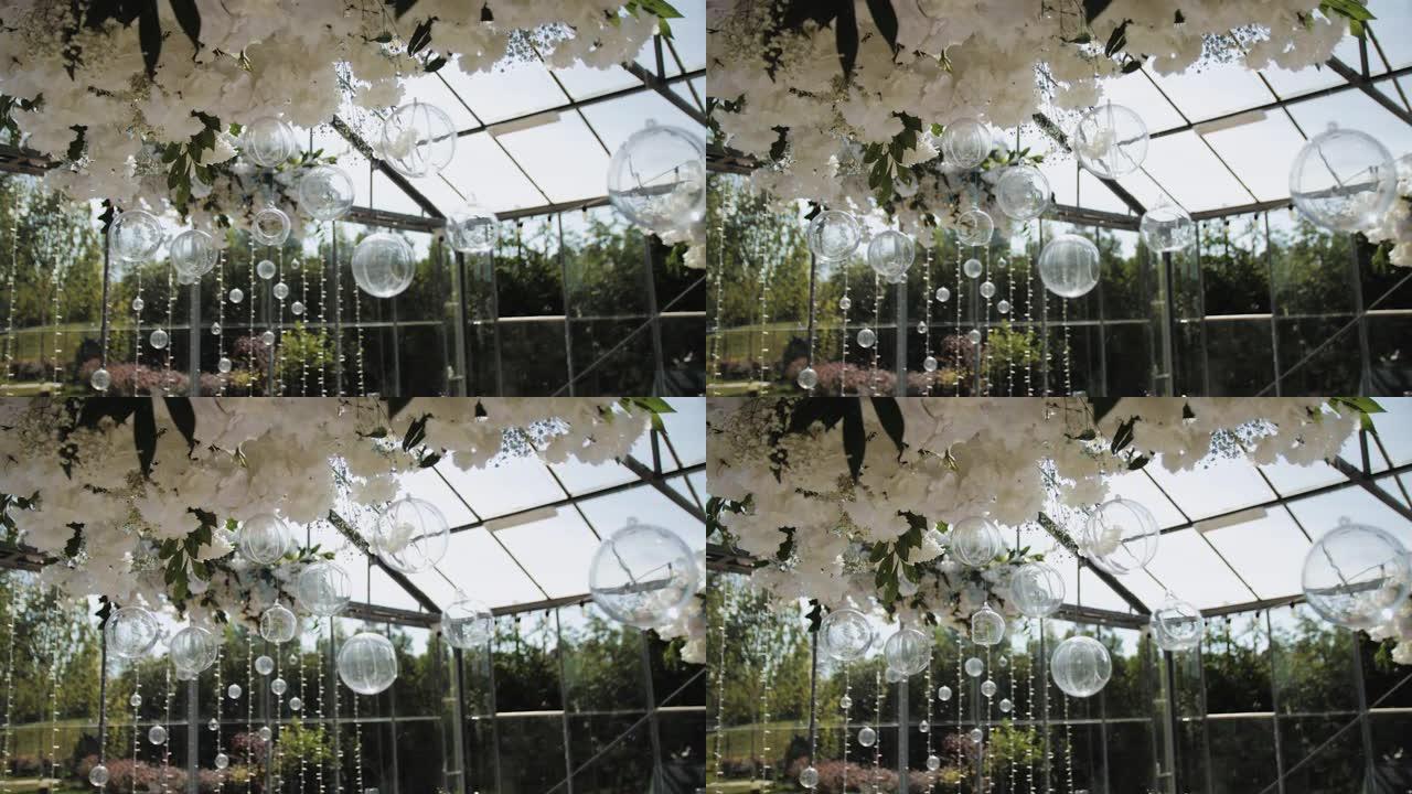 串花环上的水钻或水晶。桌子上方美丽的植物组合，白色透明玻璃装饰球，带花，慢动作。