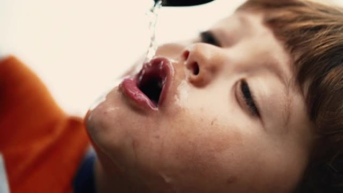 口渴的小男孩在公园用水龙头喝水。儿童补水饮料慢动作特写脸