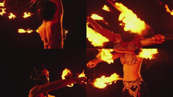 年轻女子跳舞表演酷炫危险的火表演，用火表演许多把戏。穿着黑色衣服，面具闭半边脸。晚上燃烧的铁火翅膀。