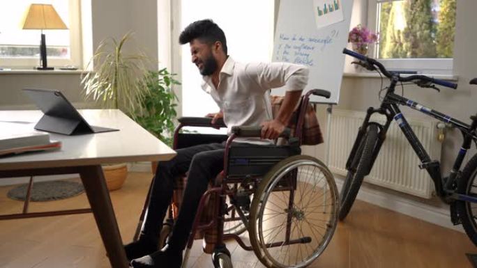 远射的年轻人激励着坐在轮椅上的中东男子站起来努力。英俊聪明的自由职业者肖像在家庭办公室室内叹息思考。