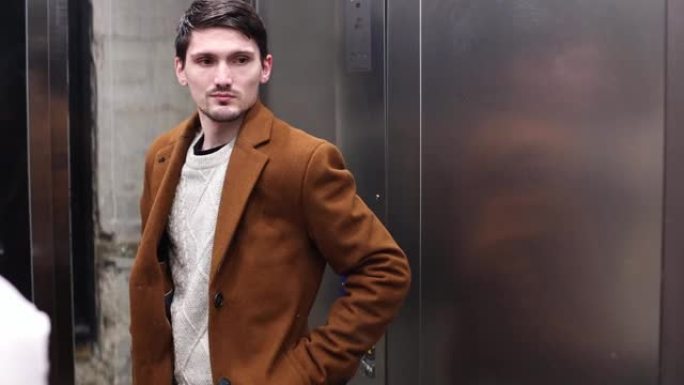 一个年轻时尚的家伙在电梯里站起来。