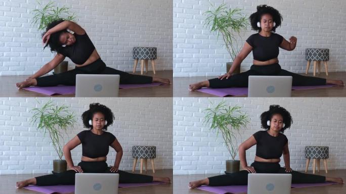 在用伸直的手臂伸到腿的脚进行锻炼后，黑人妇女慢慢抬起身体的一部分，并通过在线教练在家中通过互联网进行