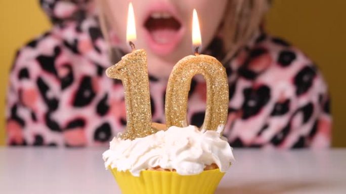 穿着豹纹工作服的快乐少女在派对上吹出生日蛋糕上的10号蜡烛。特写女孩的脸。慢动作生日快乐视频横幅。
