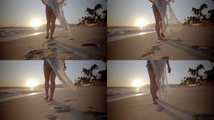 在墨西哥日落时，穿着白色海滩遮掩的女人沿着海滩散步。