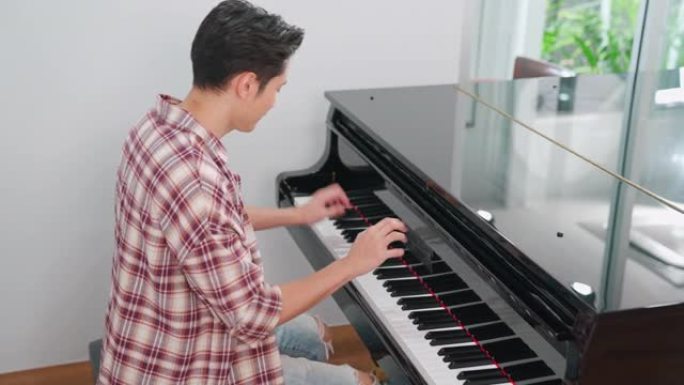 休闲风格的男钢琴家在学校演奏经典三角钢琴。专业音乐家年轻人在练习钢琴时感到快乐和放松。在线音乐学校业