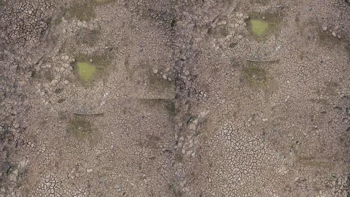 干燥的粘土土壤，带有一滩脏水和大裂缝，无人机视图