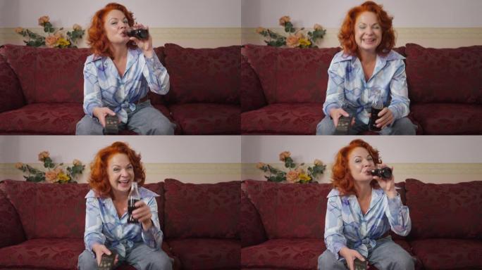 快乐的复古女人笑着喝苏打水在20世纪80年代20世纪70年代的电视上看喜剧节目。前视图肖像放松无忧无