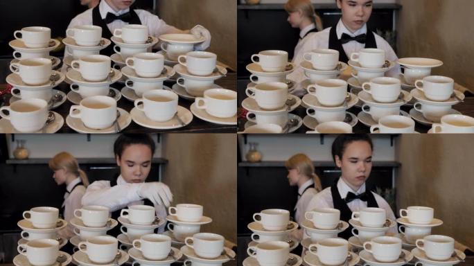 女服务员在现代餐厅为工作日准备茶杯套装。