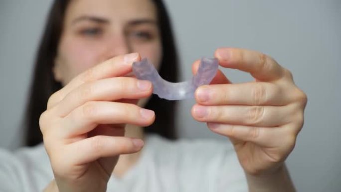 一名妇女显示牙科护齿，夹板用于治疗颞下颌关节功能障碍，磨牙症，错牙合畸形，以放松颌骨的肌肉。