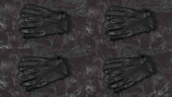 黑色皮革手套，深色纹理背景。顶视图。