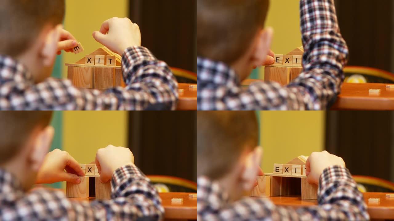 7-8岁的高加索男孩玩立方体，用铭文出口盖房子。小建筑商工程师建造了一座玩木制立方体的建筑。选择性聚