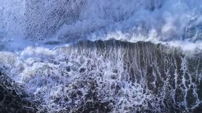 火山黑沙滩和印度洋美丽海浪飞行无人机的俯视图