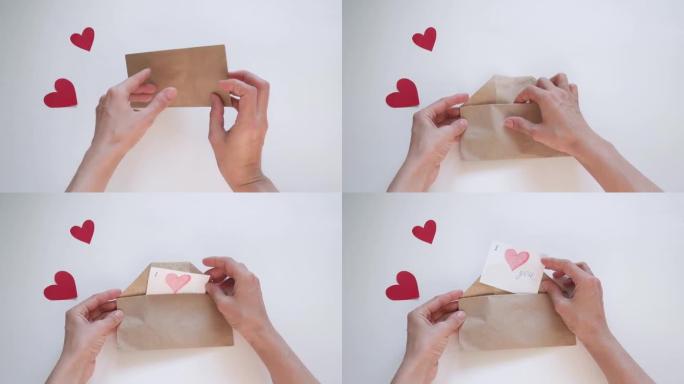 双手打开一个交付的信封，信封上有一个红色的心形情人节。爱情宣言，关系概念