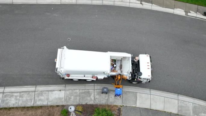 废物设施卡车的俯视图，因为它将回收物从路缘装载到有效载荷中。