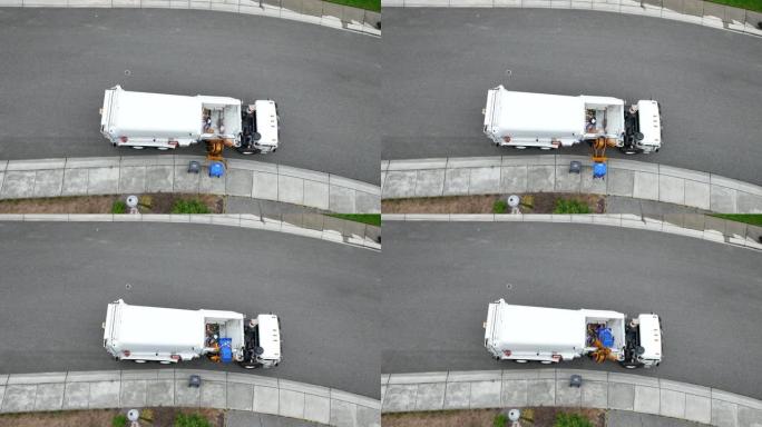 废物设施卡车的俯视图，因为它将回收物从路缘装载到有效载荷中。