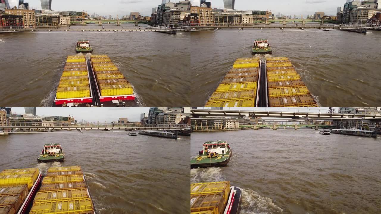 泰晤士河上拖着货物驳船的一艘船的无人机视图。