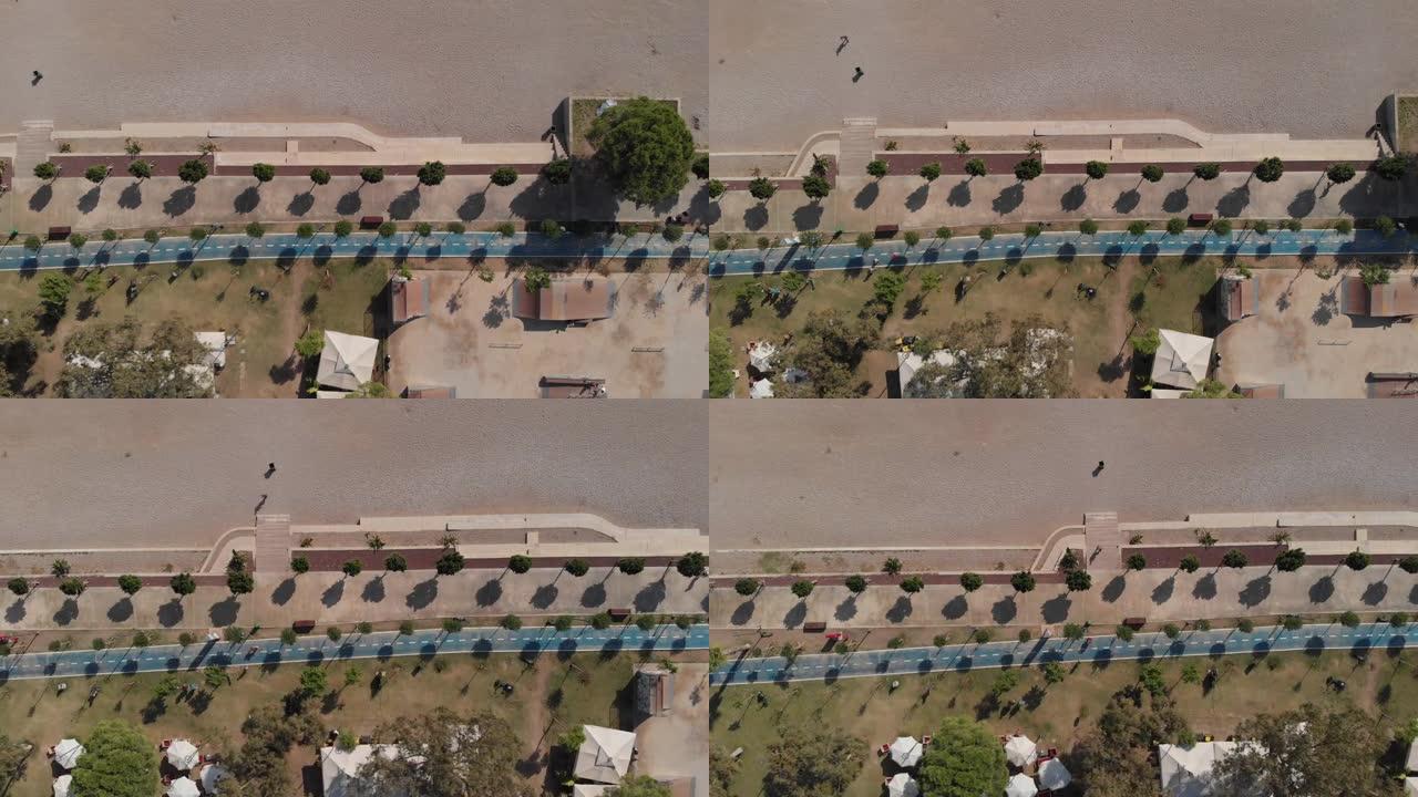 摄像机沿着海滩飞过一条设备齐全的蓝色慢跑跑道。