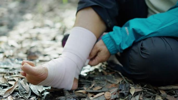收起一个痛苦的脚踝，在一个70岁的老妇人享受冒险徒步旅行后，附上弹性绷带，一个遭受痛苦的人的身体，在