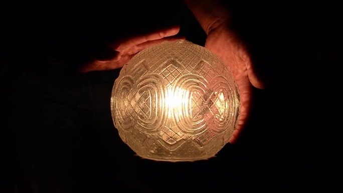 女人将手移到一个可能被咒语照亮的玻璃球上