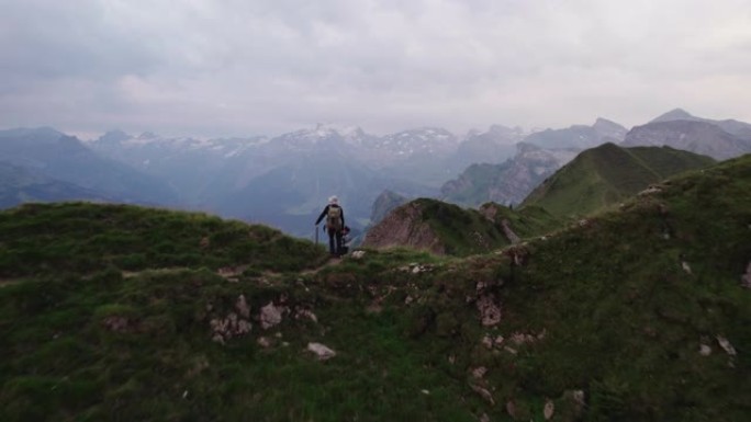 日落时沿着山脊线的徒步旅行者的空中无人机拍摄