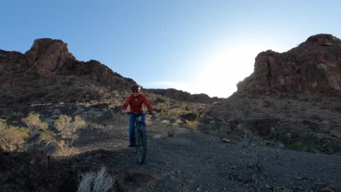 成熟的男性山地自行车手下降沙漠小径